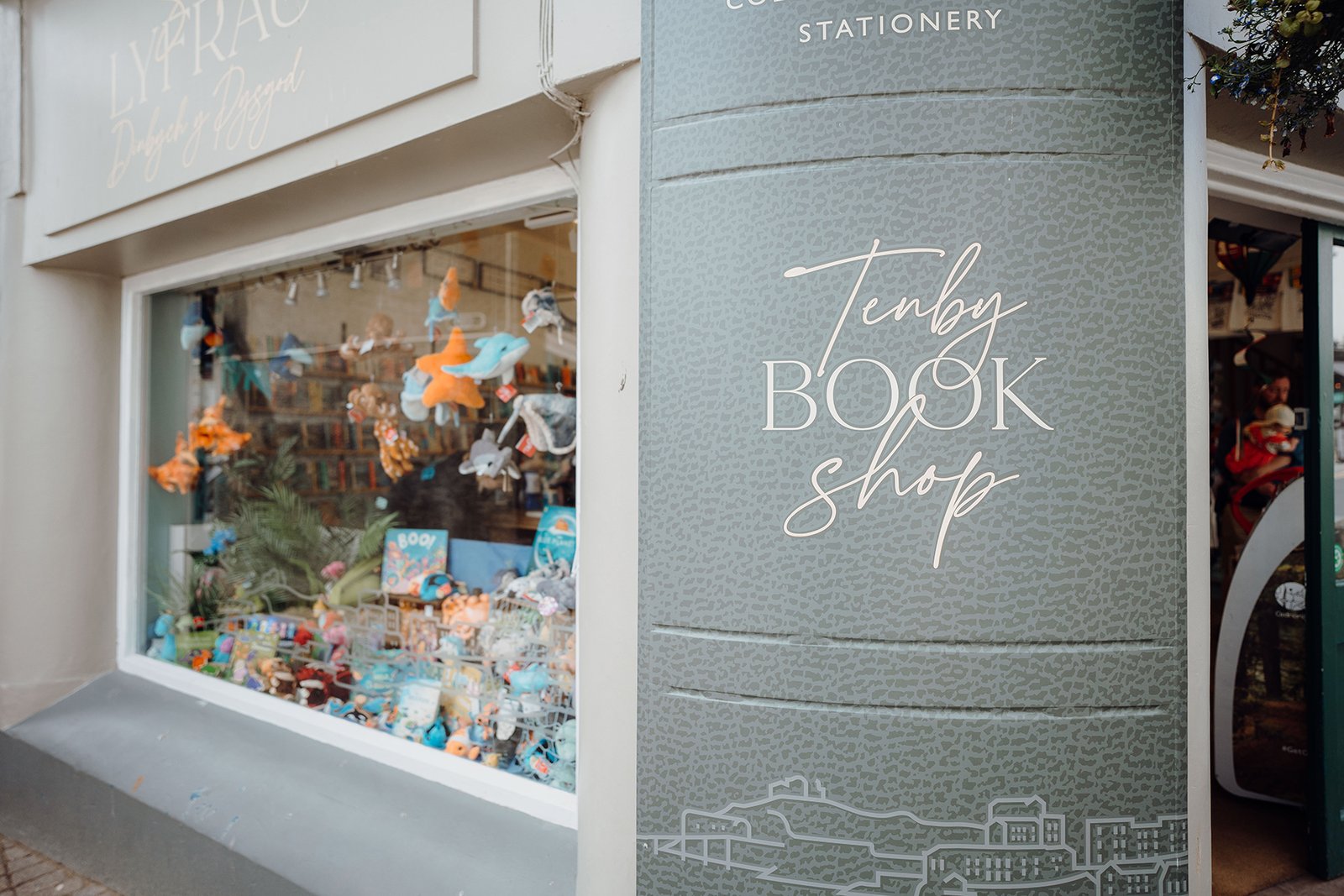 Interior of Tenby Book Shop on Tudor Square, view across the ground-floor shelves toward the front window.